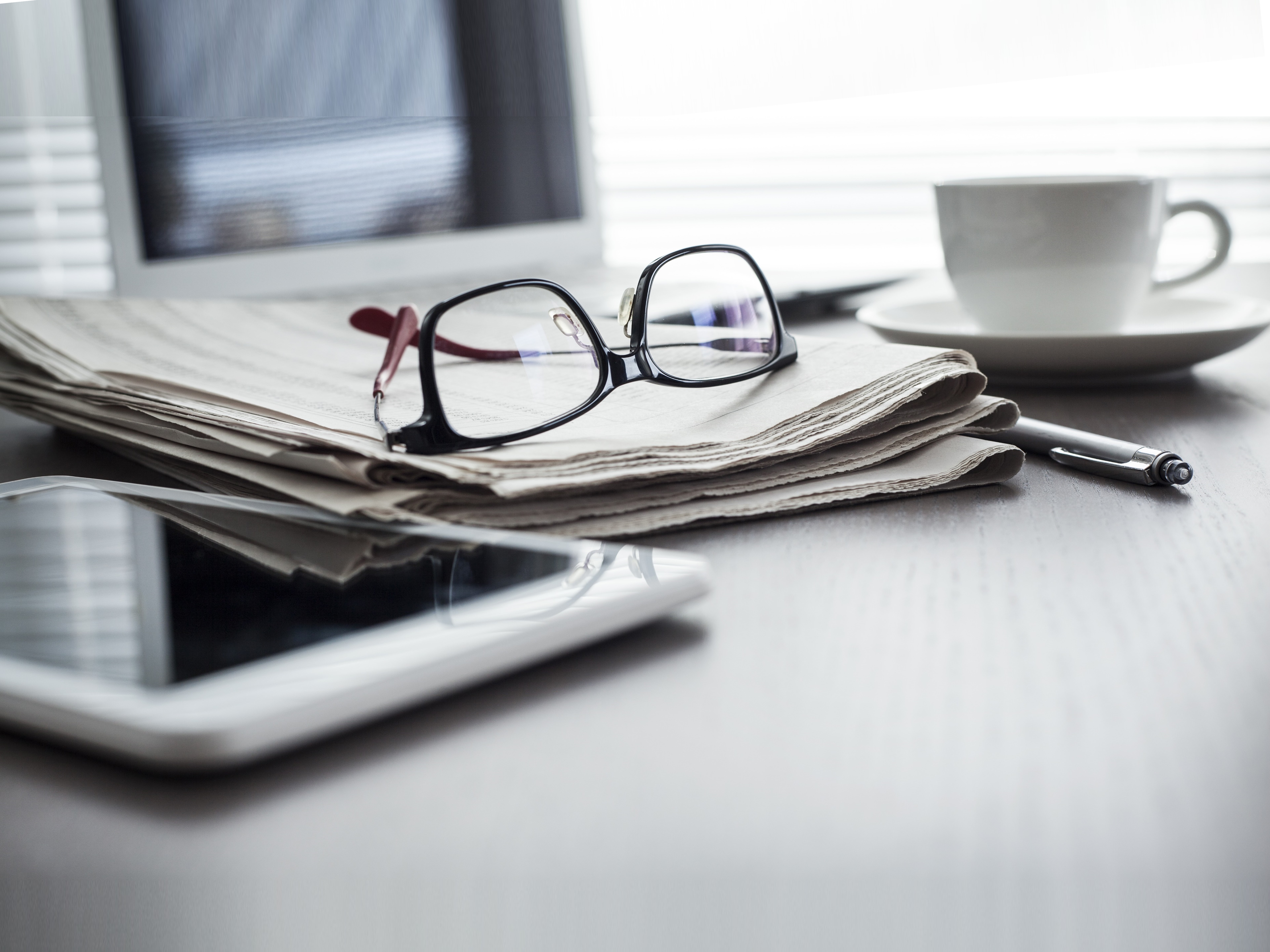 A picture of a desk with a computer glasses and cup of tea